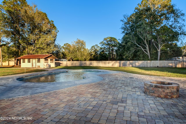 view of swimming pool featuring a patio, an outdoor fire pit, and an outdoor structure