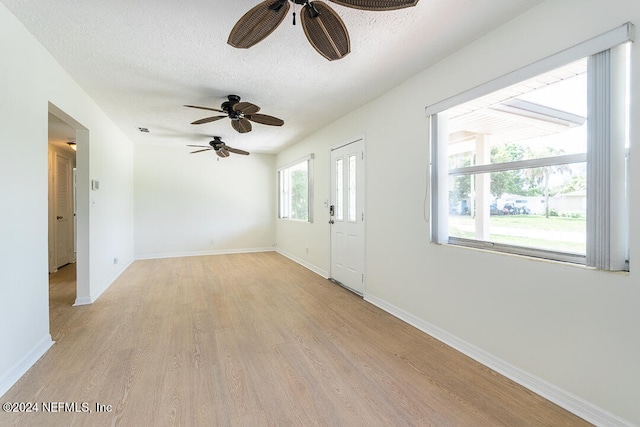 unfurnished room with ceiling fan, light hardwood / wood-style floors, and a textured ceiling