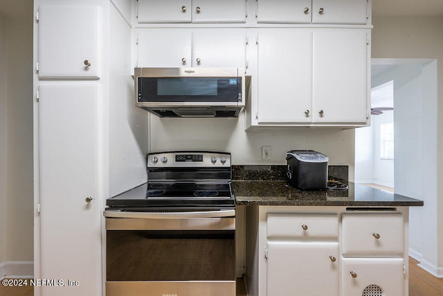 kitchen with white cabinets, stainless steel appliances, and dark stone counters