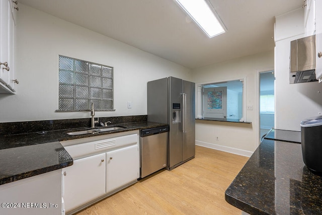 kitchen with white cabinetry, sink, dark stone countertops, appliances with stainless steel finishes, and light wood-type flooring