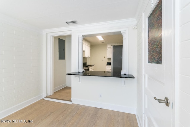 kitchen with kitchen peninsula, light hardwood / wood-style floors, electric panel, white cabinetry, and a breakfast bar area