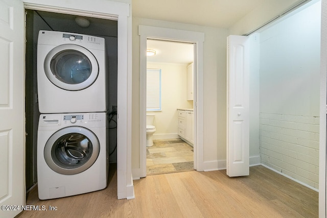 clothes washing area featuring stacked washer and dryer and light hardwood / wood-style flooring