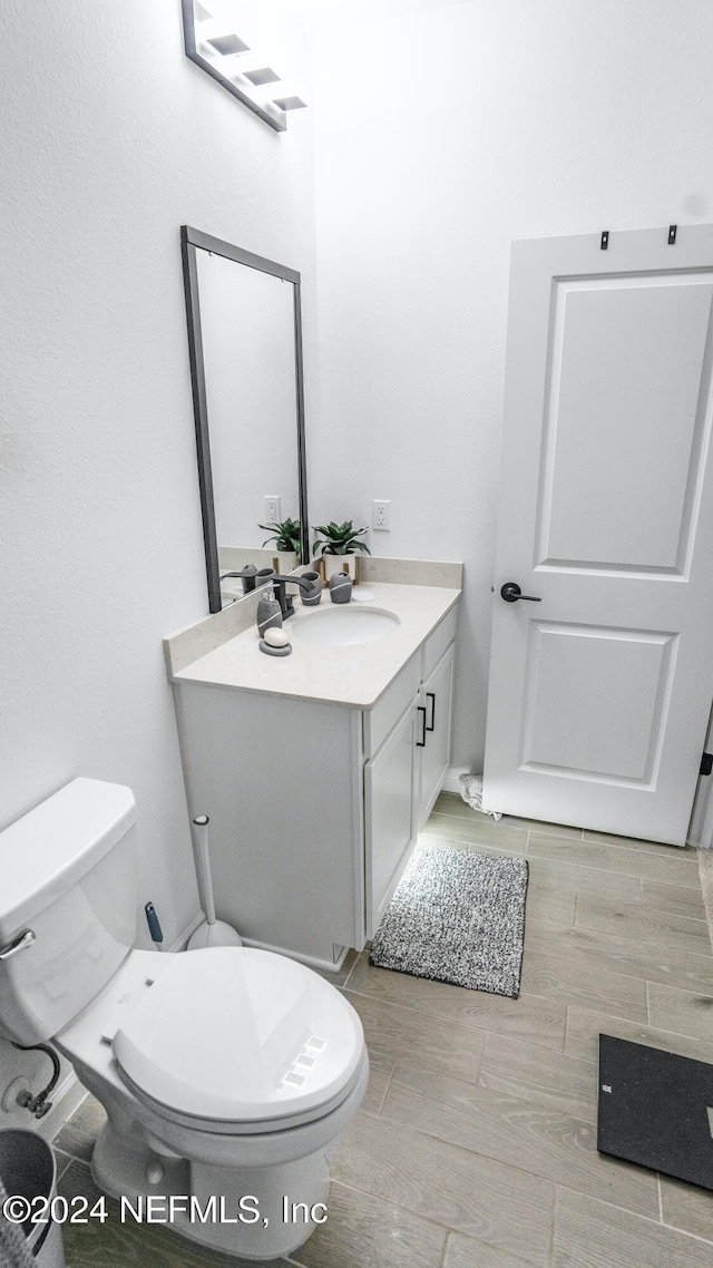 bathroom with vanity, toilet, and wood-type flooring