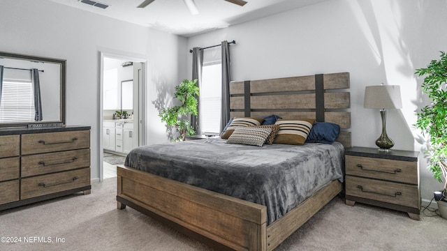 bedroom with light colored carpet, ensuite bath, and ceiling fan