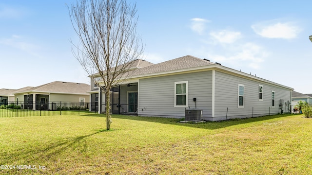 back of house with a lawn, a sunroom, and central AC