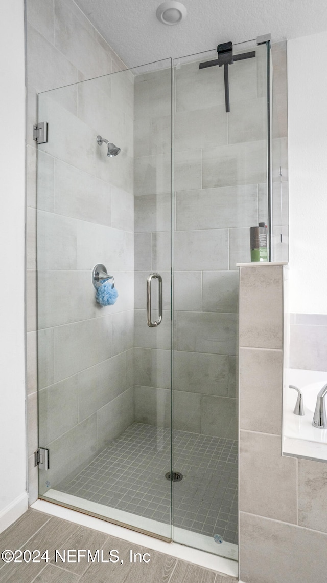 bathroom with a shower with shower door and a textured ceiling