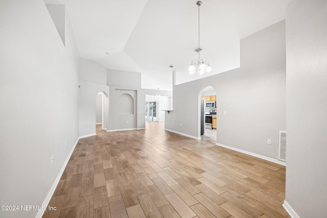 unfurnished living room with a notable chandelier, vaulted ceiling, and light hardwood / wood-style flooring