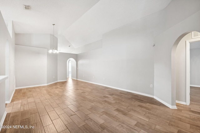 unfurnished room with light hardwood / wood-style floors, lofted ceiling, and an inviting chandelier