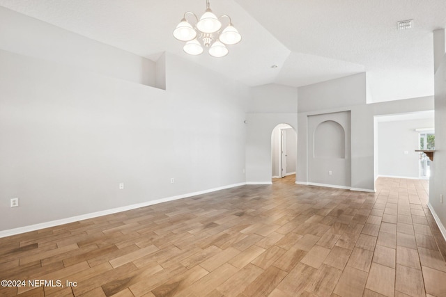 unfurnished living room with light hardwood / wood-style flooring, high vaulted ceiling, a textured ceiling, and an inviting chandelier