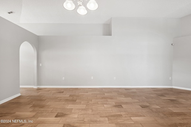 spare room featuring a chandelier and light hardwood / wood-style flooring