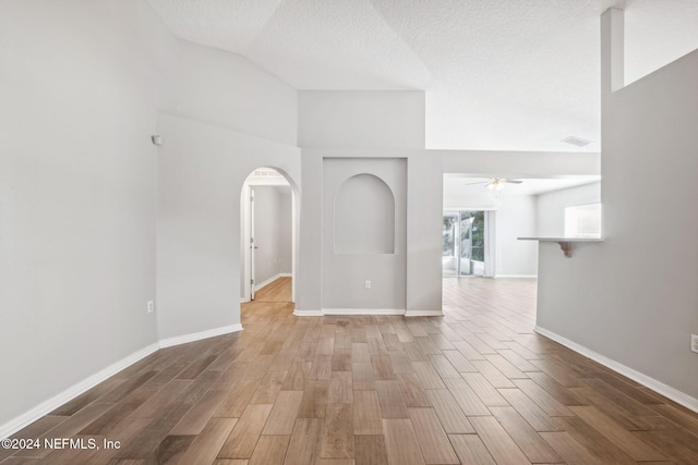 unfurnished room with ceiling fan, high vaulted ceiling, a textured ceiling, and hardwood / wood-style flooring