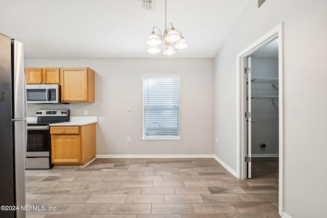 kitchen with a textured ceiling, decorative light fixtures, a notable chandelier, and appliances with stainless steel finishes