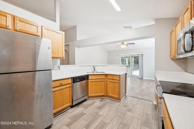 kitchen with sink, kitchen peninsula, light hardwood / wood-style floors, vaulted ceiling, and appliances with stainless steel finishes