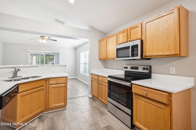 kitchen with stainless steel appliances, light hardwood / wood-style floors, lofted ceiling, and sink