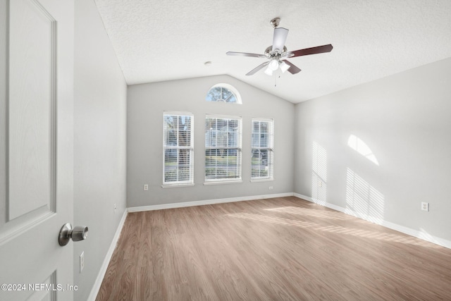 unfurnished room with a textured ceiling, light hardwood / wood-style floors, ceiling fan, and lofted ceiling