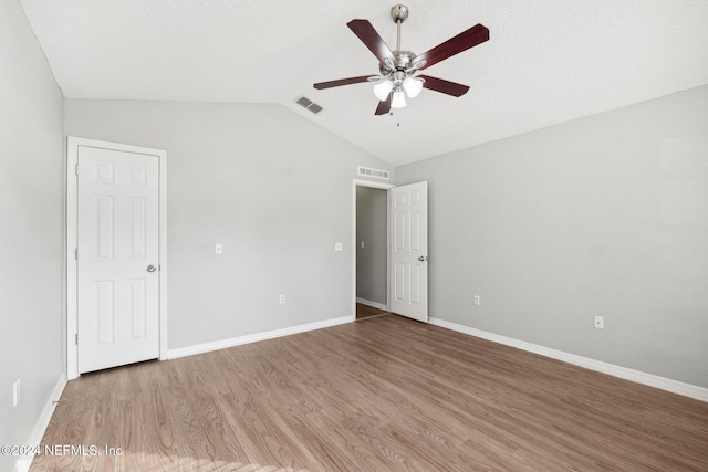 spare room with ceiling fan, light wood-type flooring, and vaulted ceiling