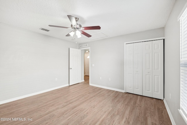 unfurnished bedroom featuring a closet, ceiling fan, light hardwood / wood-style flooring, and a textured ceiling