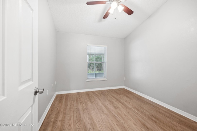 unfurnished room featuring a textured ceiling, light hardwood / wood-style floors, vaulted ceiling, and ceiling fan