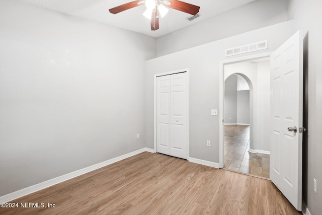 unfurnished bedroom featuring ceiling fan, a closet, and light wood-type flooring