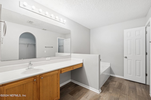 bathroom with hardwood / wood-style floors, vanity, a bathing tub, and a textured ceiling