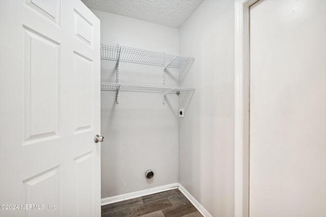 laundry room with dark wood-type flooring, a textured ceiling, and hookup for an electric dryer