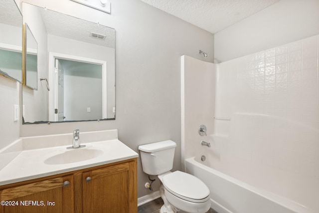 full bathroom featuring washtub / shower combination, vanity, a textured ceiling, and toilet