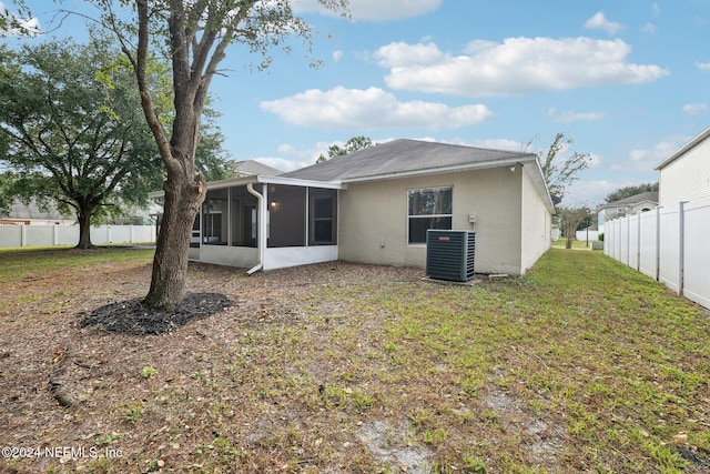 back of property with a yard, central air condition unit, and a sunroom