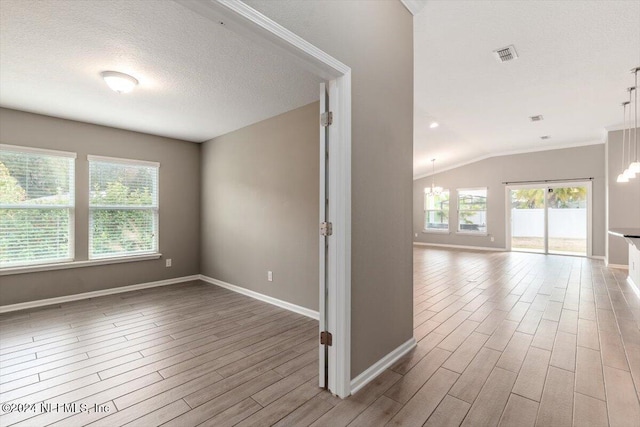 hall featuring hardwood / wood-style floors, a chandelier, a textured ceiling, and vaulted ceiling