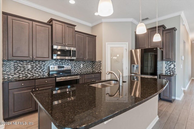 kitchen with decorative light fixtures, an island with sink, stainless steel appliances, and sink