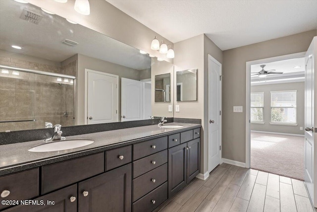 bathroom featuring vanity, a textured ceiling, ceiling fan, hardwood / wood-style floors, and a shower with shower door