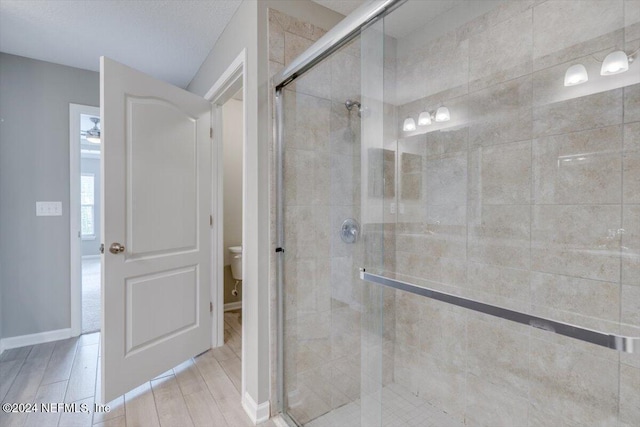 bathroom with hardwood / wood-style flooring, toilet, and an enclosed shower