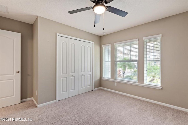 unfurnished bedroom featuring a closet, ceiling fan, and light colored carpet