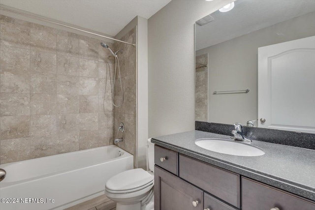 full bathroom with vanity, tiled shower / bath, a textured ceiling, and toilet