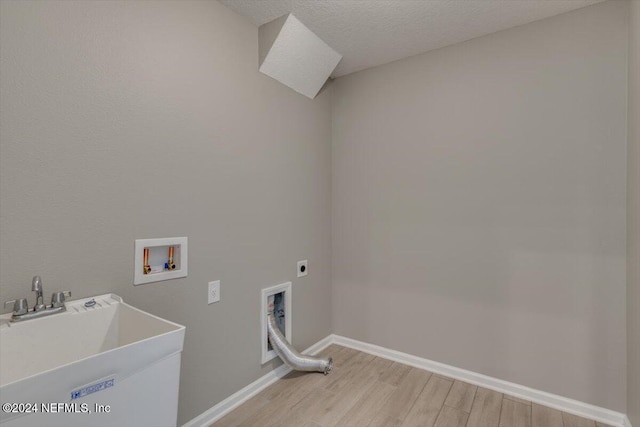 laundry area featuring washer hookup, a textured ceiling, electric dryer hookup, sink, and light hardwood / wood-style flooring