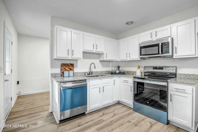 kitchen with sink, light stone countertops, appliances with stainless steel finishes, light hardwood / wood-style floors, and white cabinetry