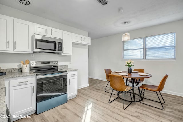 kitchen featuring white cabinetry, stainless steel appliances, decorative light fixtures, and light wood-type flooring