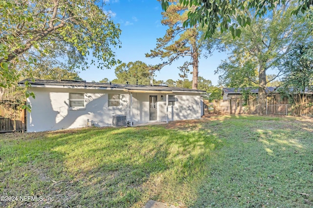 rear view of house with a lawn and central AC unit