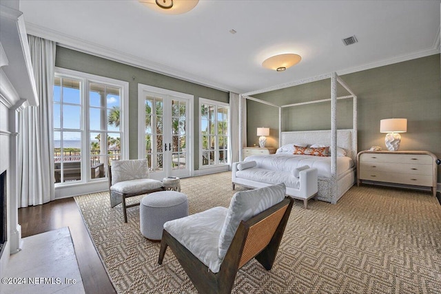 bedroom featuring a fireplace, wood-type flooring, french doors, and crown molding