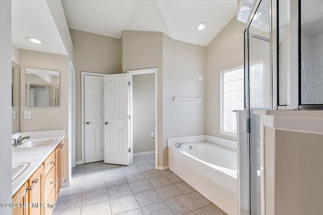 bathroom with tile patterned floors, a washtub, vanity, and vaulted ceiling