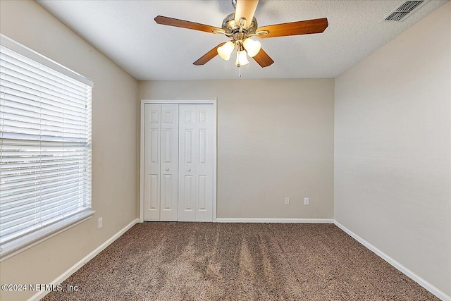 unfurnished bedroom featuring carpet, a closet, multiple windows, and ceiling fan