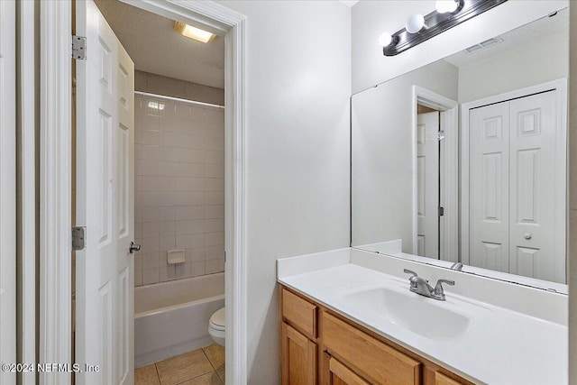 full bathroom featuring a textured ceiling, vanity, tiled shower / bath combo, tile patterned flooring, and toilet