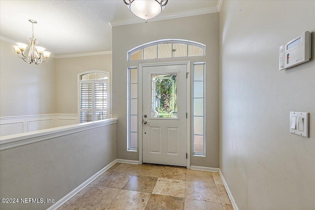 entrance foyer featuring a textured ceiling, crown molding, and a notable chandelier