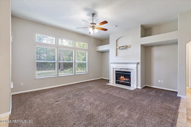 unfurnished living room featuring carpet, ceiling fan, and a textured ceiling