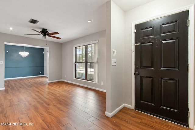 foyer with hardwood / wood-style floors and ceiling fan with notable chandelier