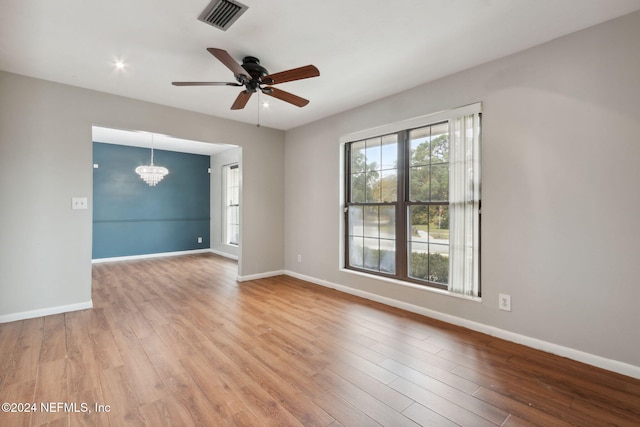 unfurnished room with ceiling fan with notable chandelier and hardwood / wood-style flooring