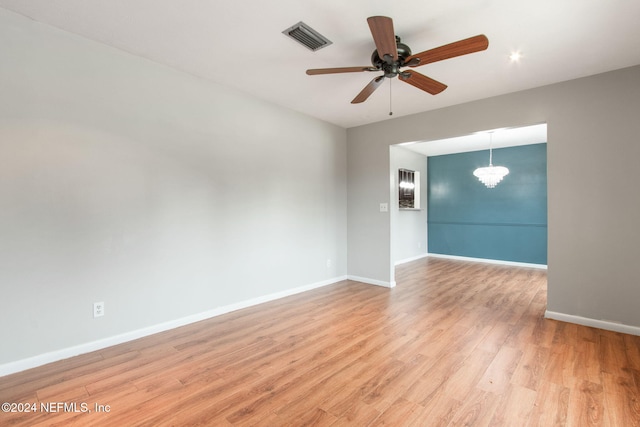 empty room featuring light hardwood / wood-style floors and ceiling fan with notable chandelier