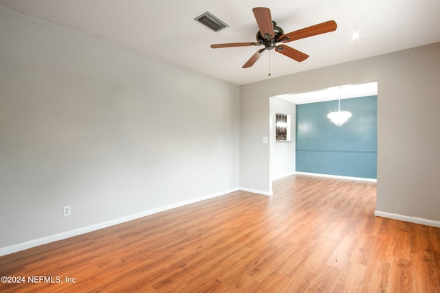 unfurnished room featuring ceiling fan with notable chandelier and light wood-type flooring