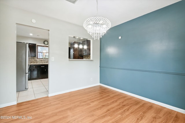 unfurnished dining area with a notable chandelier, light hardwood / wood-style floors, and sink