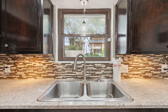 kitchen featuring backsplash, sink, pendant lighting, and dark brown cabinets