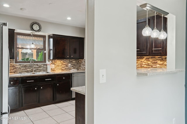 kitchen featuring decorative backsplash, dark brown cabinetry, sink, light tile patterned floors, and hanging light fixtures